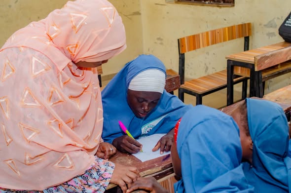 A facilitator supports a schoolgirl during a learning activity.